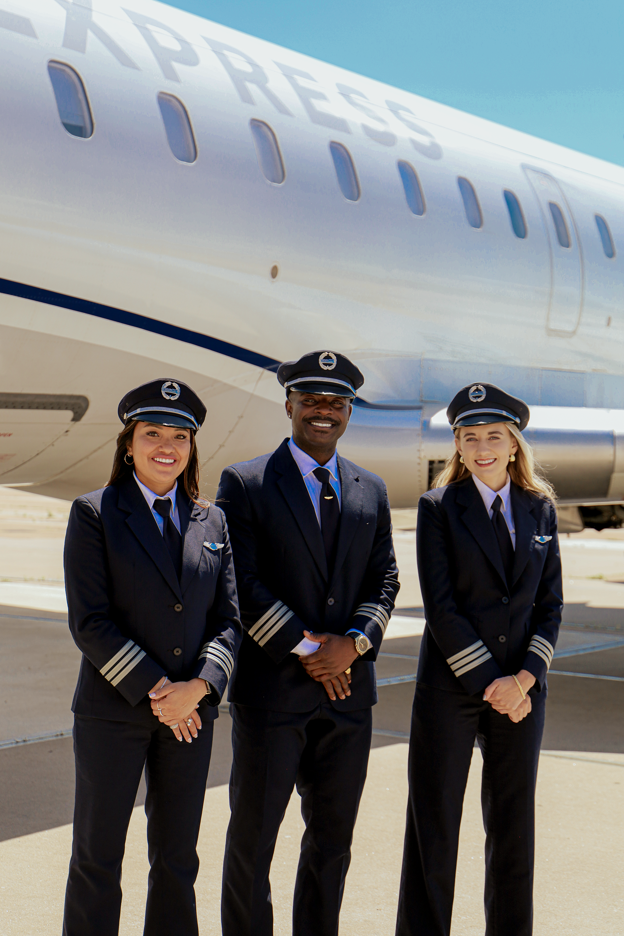 Two female and one male first officers in front of the CRJ-550